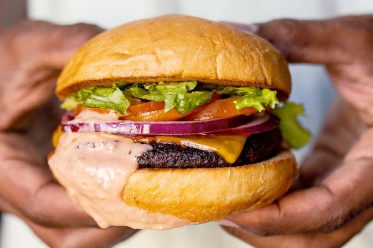 A person holiding a burger