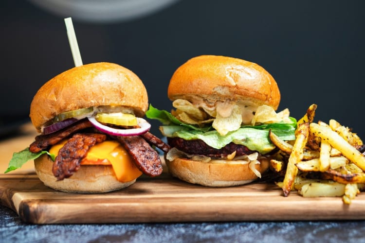 Two burgers and fries on a wooden board