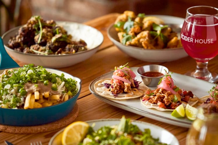 A selection of food and glasses of cider on a wooden table