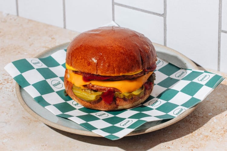 A veggie burger on a plate with green and white paper