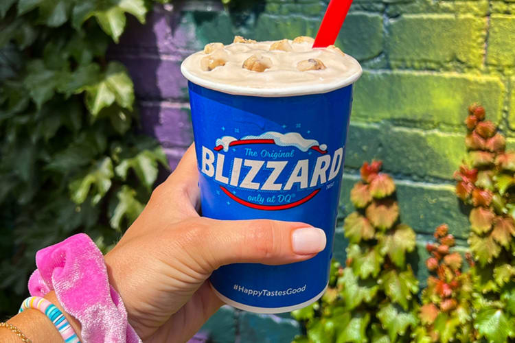 A person holding frozen custard in a blue cup