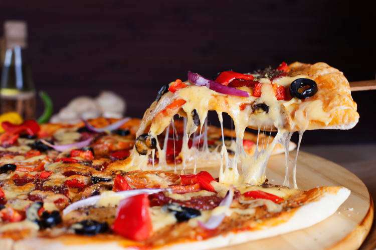 Slice of a vegetarian pizza being lifted from the rest 