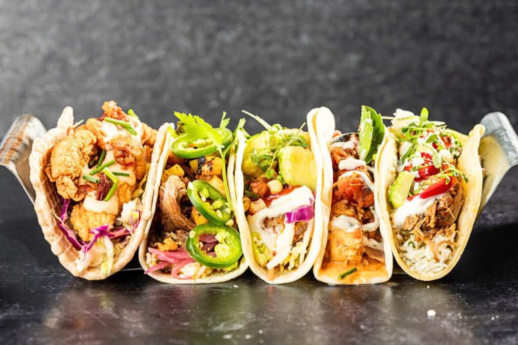 Side view of five tacos on a tray, from Velvet Taco