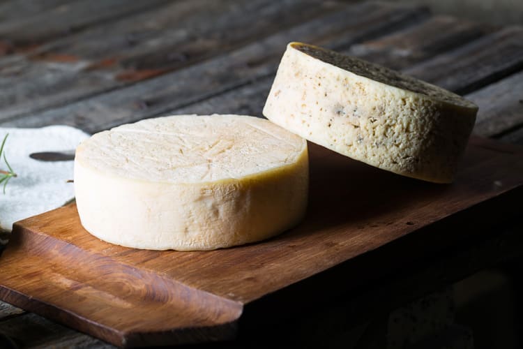 Two wheels of goat cheese on a wooden board