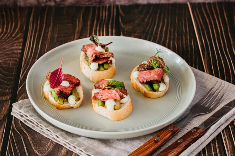 Four beef tenderloin canapé sandwiches on a plate