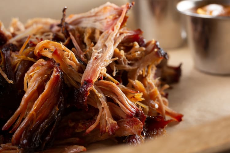 pulled pork smothered in barbecue sauce on a wooden table