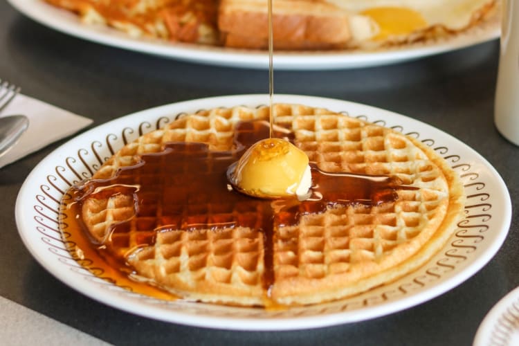 A waffle with syrup being poured onto it