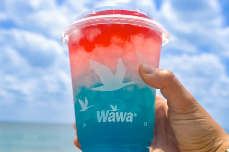 A person holding up a red and blue iced drink