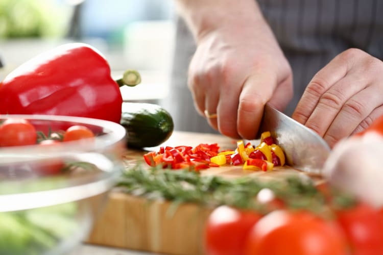 A person chopping sweet peppers for cooking.