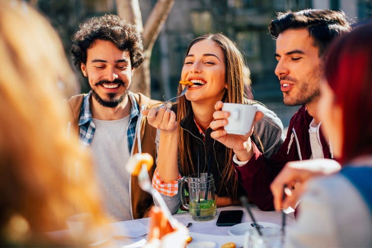 Five friends enjoying breakfast while chatting and laughing