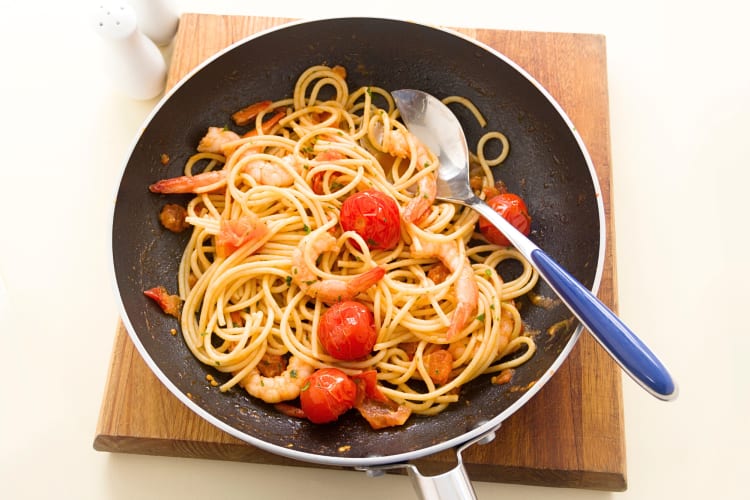 Shrimp and tomato spaghetti dish in a pan with a spoon in it