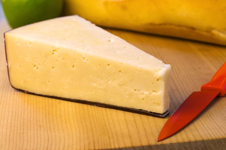 Block of Asiago cheese with a knife next to it