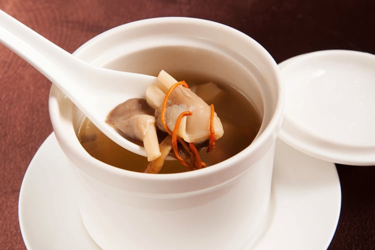 A spoon lifting mushrooms out of a bowl of hibachi soup