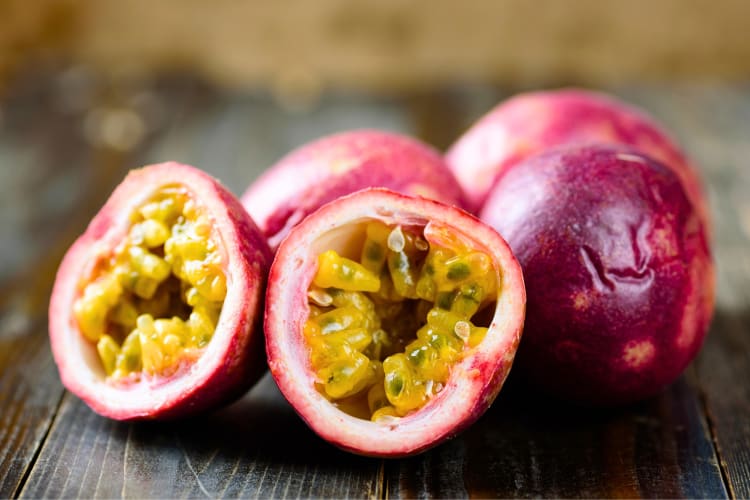 Whole and halved passion fruit on a wooden surface