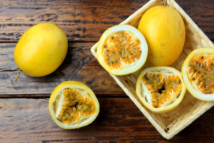 Whole and halved yellow passion fruits on a wooden surface