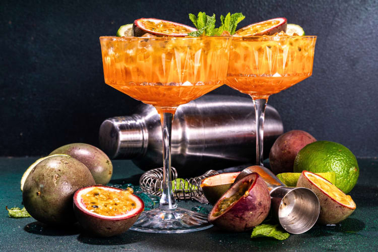 Passion fruit cocktails surrounded by ingredients and a cocktail shaker