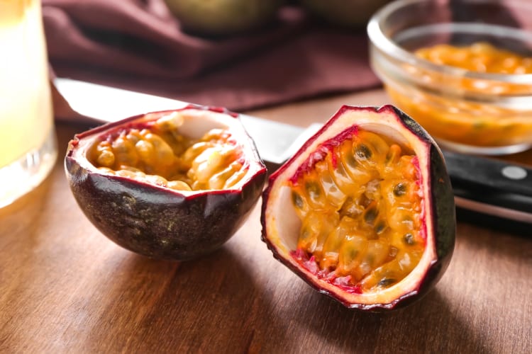 A passion fruit on a chopping board next to a knife