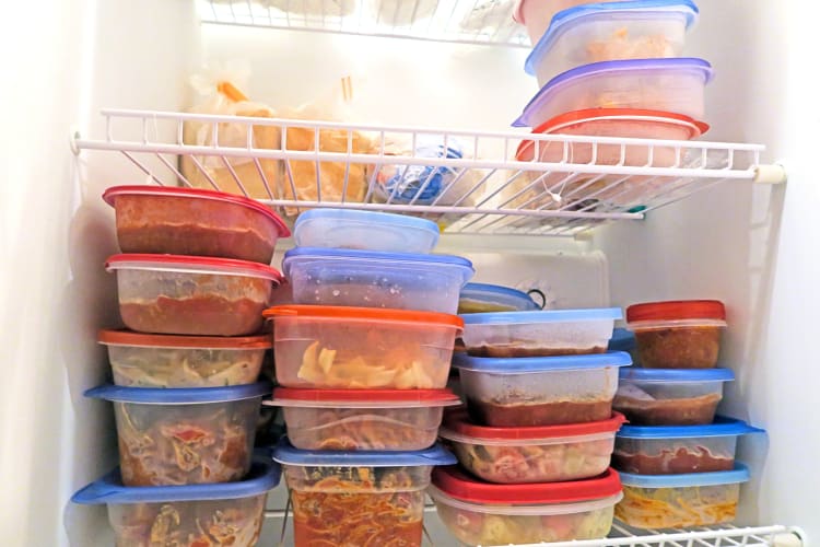 Containers in a freezer with a variety of foods in them