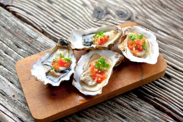 Four oysters on a wooden surface