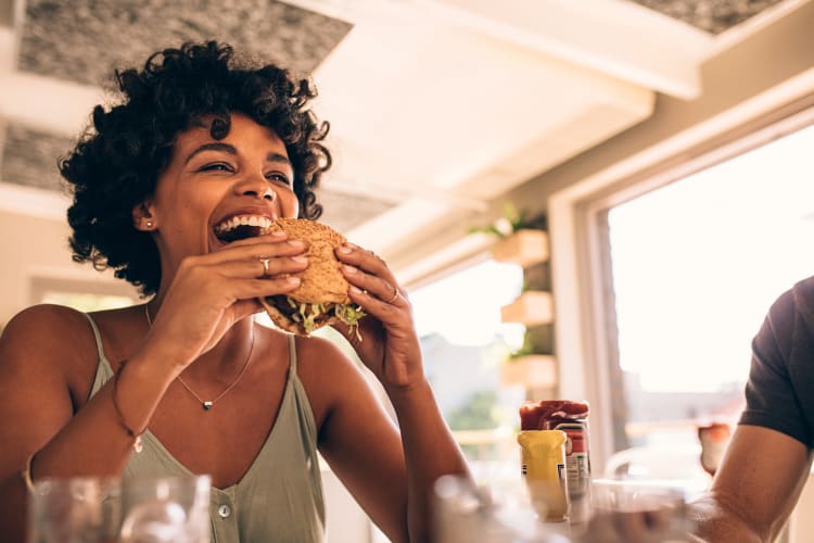 Woman holding a burger she's about to bite into