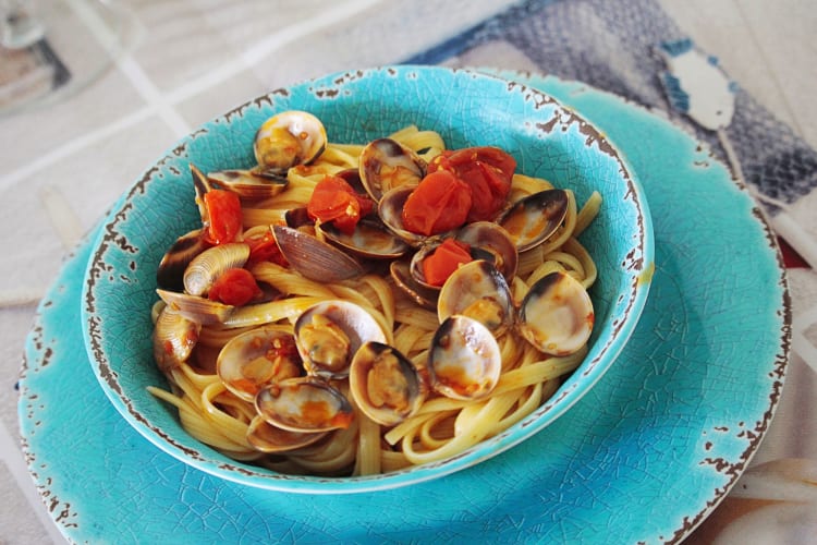 Linguine pasta dish with clams and tomatoes, in a blue bowl