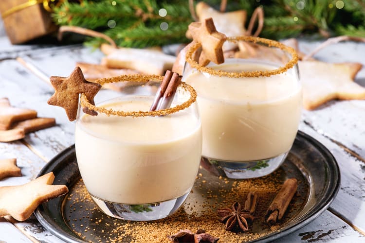 Two glasses of eggnog with cinnamon stick and gingerbread cookie garnish