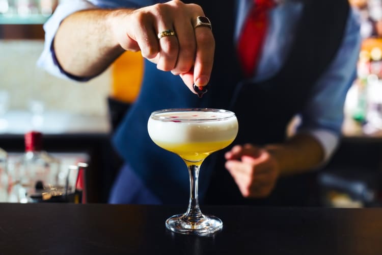 A bartender making a cocktail in a coupe glass