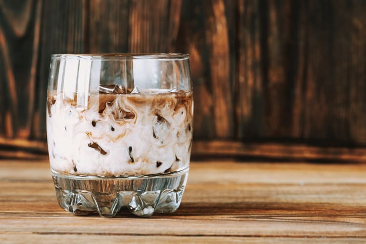 Eye-level view of a white Russian vodka cocktail on a wooden surface