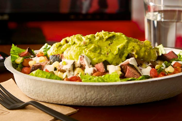 A Chipotle bowl with vegetables, meat and guacamole