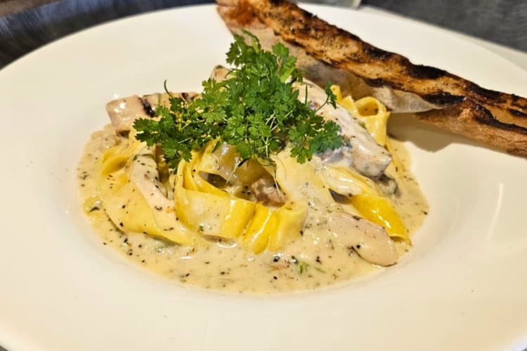 Creamy pasta with a breadstick on the side from Wild Root Café