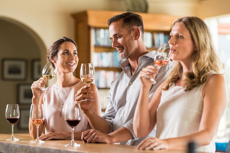 Three people chatting and tasting wine together