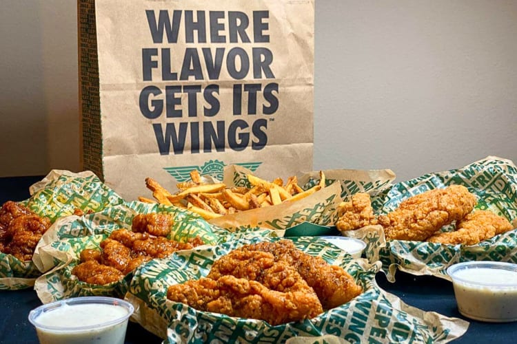 Fast food chicken tenders, fries and wings, in front of a paper bag, from Wingstop