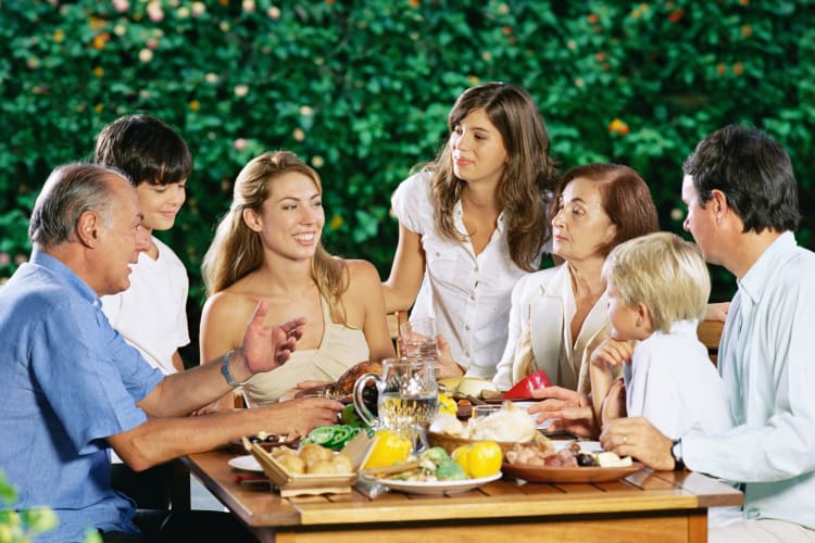 Family of seven chatting and laughing over dinner