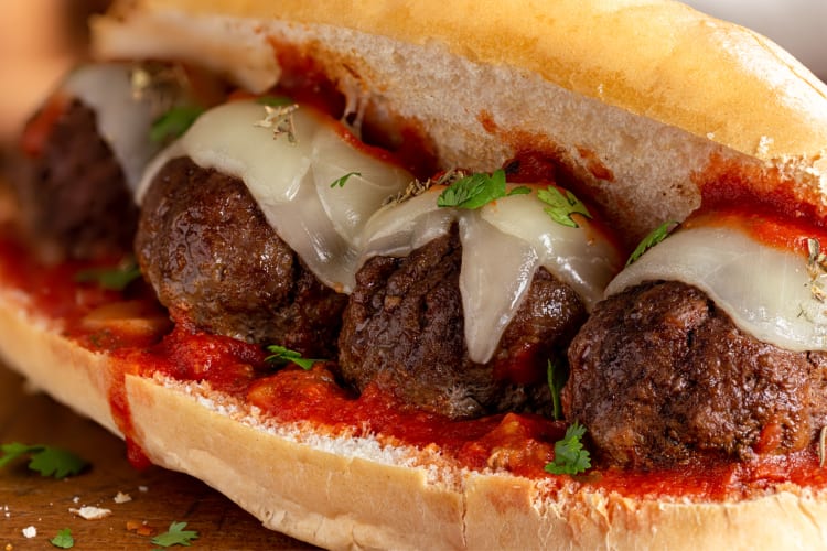 Close-up shot of a meatball sub with melted cheese on top of the meatballs