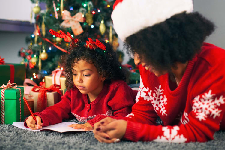 A mother watching her daughter write a letter to Santa