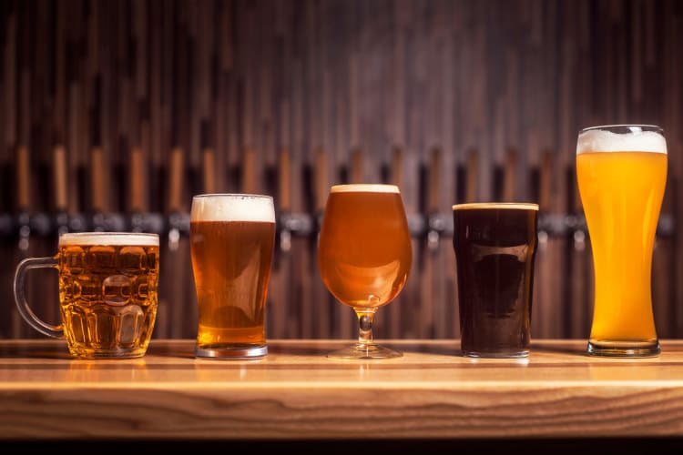 Glasses of beer lined up on a bar