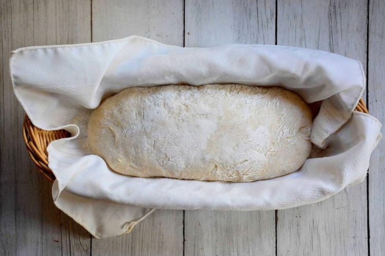 Bread proving in a wicker basket with a cloth