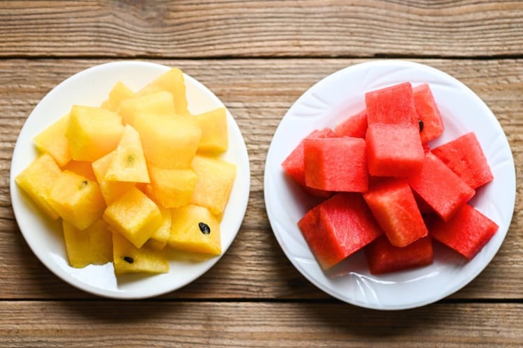 Yellow watermelon pieces on a plate next to pieces of red watermelon