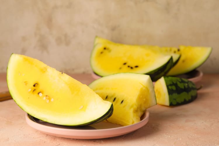 Slices of cut yellow watermelon on plates