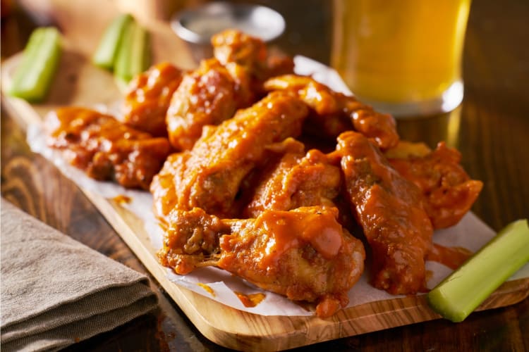 Buffalo chicken wings on wooden board with celery