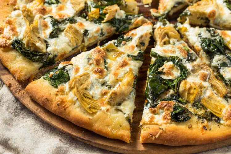 Artichoke spinach pizza served on a wooden table