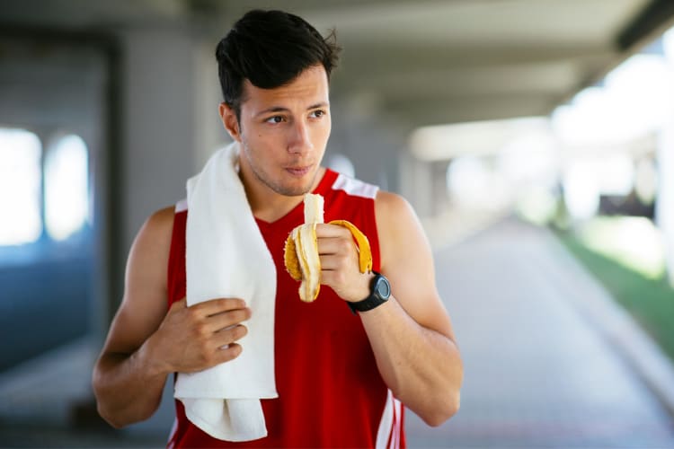 A man in workout clothes eating a banana