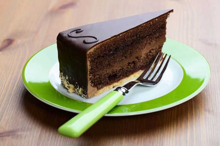 A slice of Sachertorte and a fork on a green and white plate