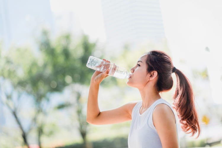 A woman drinking one of the best bottled water brands.