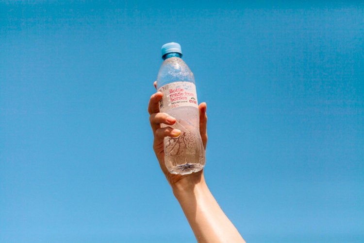A bottle of Evian water held up to the sky.
