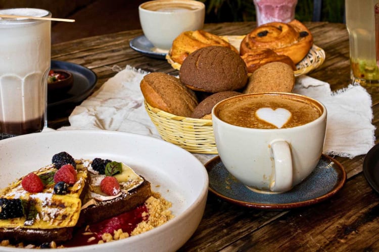 French toast, bread, pastries and coffee on a wooden table.