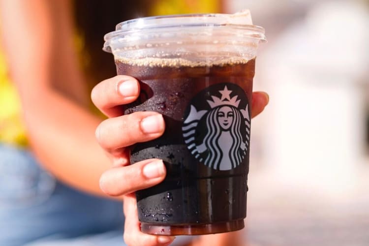 A hand holding a Iced Caffè Americano, one of the best cold coffees at Starbucks