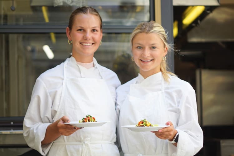 Two students holding their prepared dishes