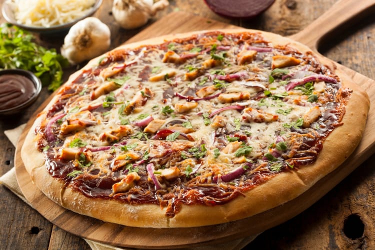 A pizza with chicken, red onion and barbecue sauce