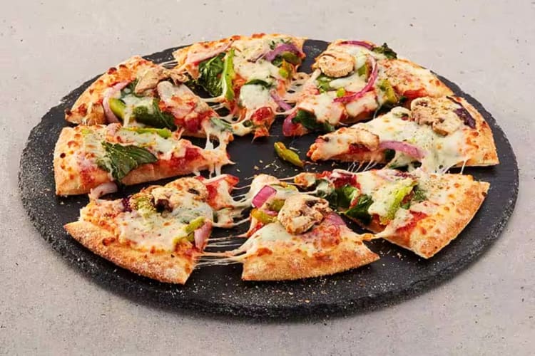 A pizza from Domino's with spinach, onions, mushrooms and tomatoes